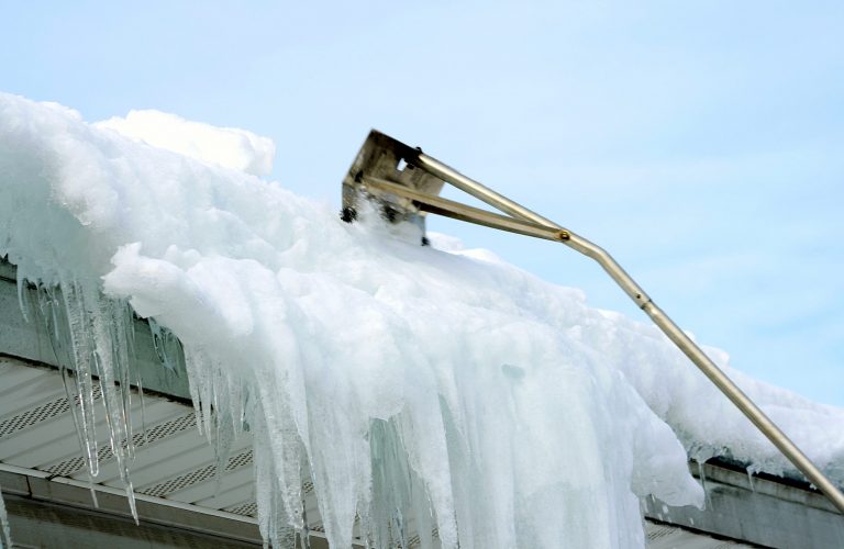 abstract of snow rake removing snow from roof after winter storm